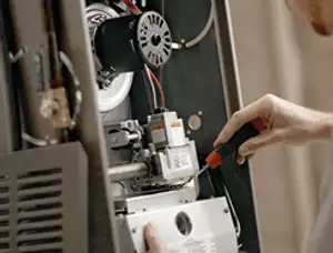 Furnace repair technician inspecting internal components and wiring in Indianapolis, IN