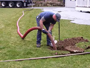 Septic pumping technician servicing a residential septic tank with a vacuum hose in Indianapolis, IN