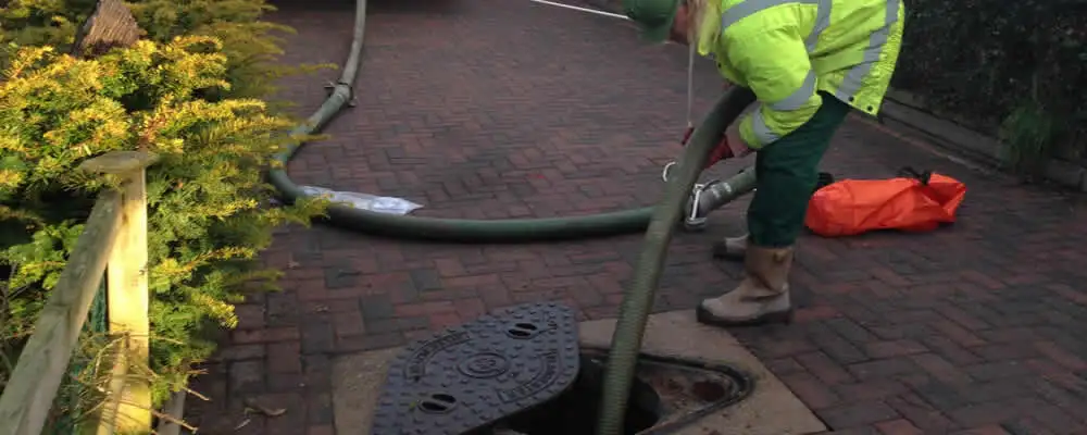 Septic tank cleaning technician servicing a septic tank with a vacuum hose in Indianapolis, IN