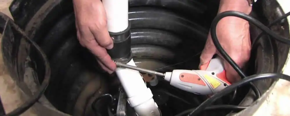 Sump pump installation technician connecting PVC discharge piping in Indianapolis, IN